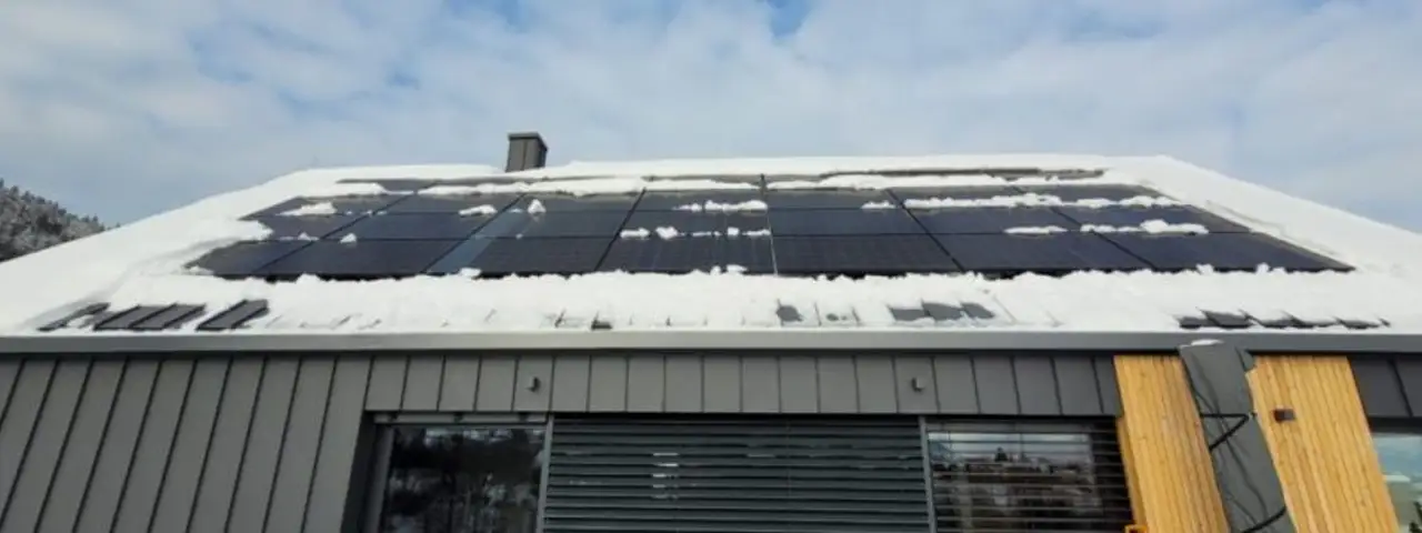 Zaśnieżony dach z zamontowanymi panelami fotowoltaicznymi